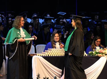 cerimônia de formatura, formando indo em direção ao professor para pegar o canudo de formatura