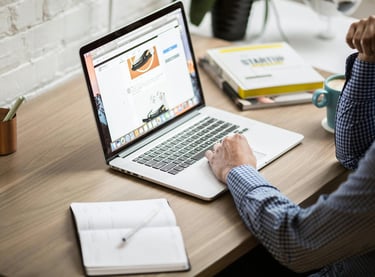 Un homme assis sur un bureau avec un ordinateur portable