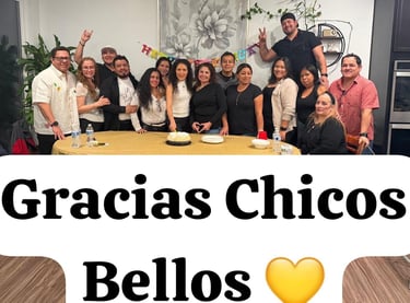 A large group of friends and family gathered around a birthday cake for a festive indoor celebration.