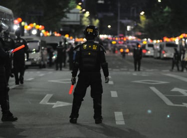 South Korean police officer in tactical gear directing night traffic with glowing batons.