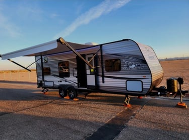 Jayco Jay Flight travel trailer with extended awning parked at a campsite during sunset.