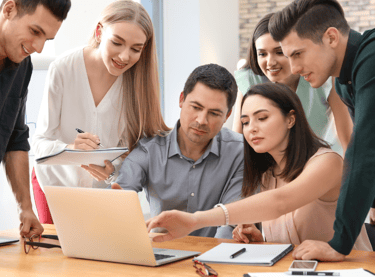 a group of people standing around a laptop computer