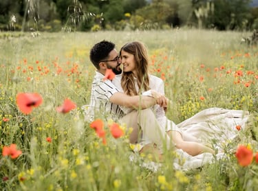 Couple sitting in a poppy field — heads together, smiling and intertwined in Provence