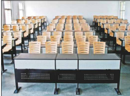 Rows of modern wooden chairs and desks in a large, empty university lecture hall or classroom.