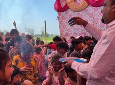 Teacher throwing blue powder over children who are having fun at Holi Festival.