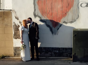 bride and groom kissing each other on the street during the golden hour 