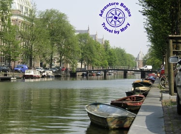 A photo of a Canal in Amsterdam with multiple boats and a bridge...taken by Mary Morong.