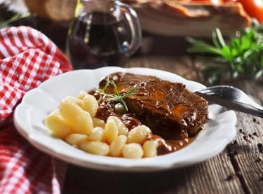 Slow-cooked beef pot roast served with potato gnocchi and rich gravy on a white plate.
