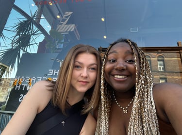 Two girls sitting in front of a store window