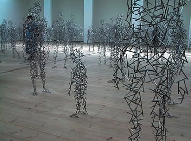 a group of people standing in a room with many metal sculptures