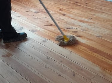 a person cleaning a hardwood floor with a broom