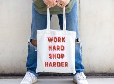 a person holding one of work hard shop harder tote bags.