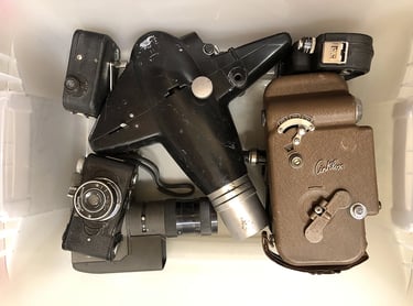A bin full of old cameras inside an assemblage artist's workshop.