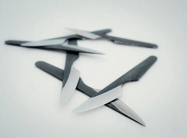 A collection of sharp steak knives with black handles on a white background.