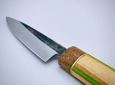 Custom Japanese petty knife with a carbon steel blade and unique cork and wood handle on a white background.