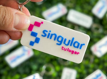 Hand holding a white rectangular custom 3D printed  3d llaveros posadas with the Singular logo.
