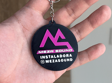 Custom 3D printed Meza Sound logo keychain in black and pink held in a hand.
