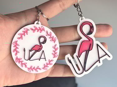 Custom 3D printed flamingo keychains featuring pink bird designs and personalized UZA text.