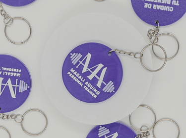 Custom purple 3D printed keychains for personal trainer Magali Aquino featuring a barbell logo.