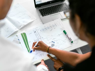 Civil engineers reviewing architectural blueprints and site plans with a laptop in an office.