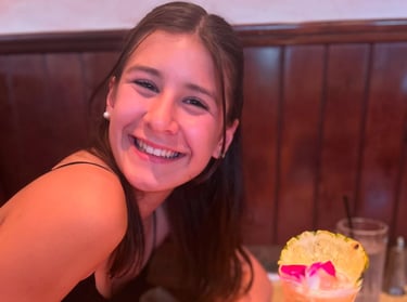 A girl sitting at a table drinking a drink