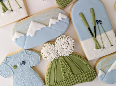 Cookies of onesies, hats, skis, and mountains for a baby shower