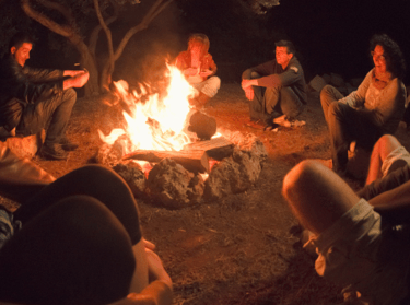 People sitting around a campfire at night