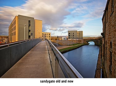 a bridge over a canal with new buildings in the background