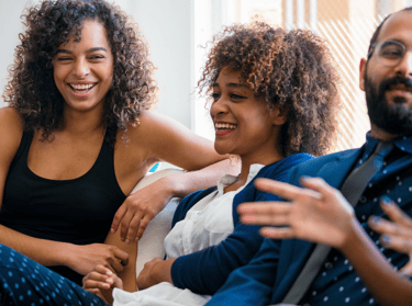 a group of people sitting on a couch laughing