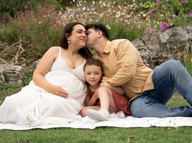 Pregnant mother holding her daughter and father kissing her cheek 