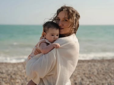 woman holding her baby on the arms by the sea