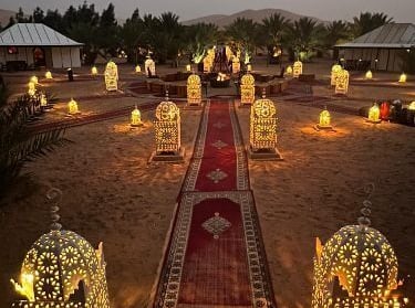 a long red carpet in desert with lamps around