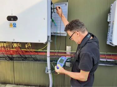 specteur voert metingen uit aan zonnestroominstallatie bij omvormer op buitenmuur