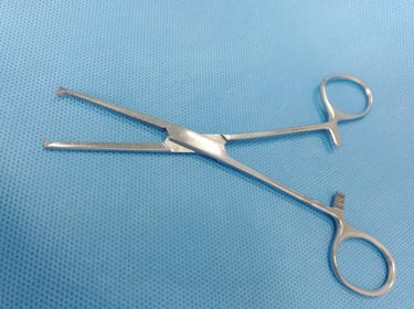 Pinça Kocher reta sobre tecido azul estéril, usada para fixar tecidos firmes.