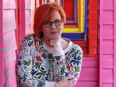 Dawn Vincent Celebrant smiling leaning on brightly coloured beach huts