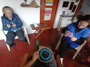 personas tejiendo juntas en costurero, en una sala con puertas de madera y elementos artesanales