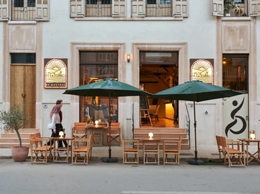 Mesas, sombrillas y cartel de Es Mestral, bajo la fachada principal del restaurante en Ses Salines.