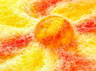 XL bath bomb producing golden yellow and orange foam with heavy fizz.