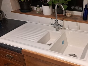 White ceramic drop-in double bowl kitchen sink with chrome mixer tap and drainer board.