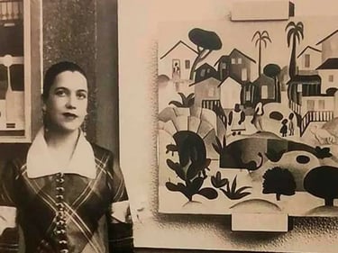 foto de Tarsila do Amaral, ao lado de uma quadro pintado por ela.
