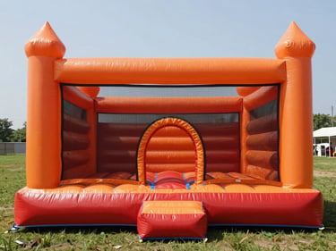 Fully inflated orange and red bounce castle staged on a flat grassy area in clean noon daylight, no occupants, front view showing the entrance arch and netting panels clearly