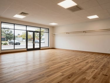 Completed commercial retail remodel interior, fresh flooring installed, new drop-ceiling grid in place, recessed lighting operational, empty and ready for occupancy, overcast natural daylight from storefront glazing