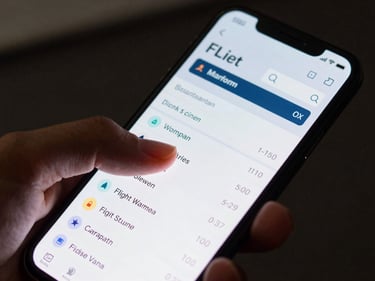 Close-up of a hand scrolling through a flight booking app on a smartphone screen, digital screen glow illuminating fingers, dark background, sharp focus on the screen interface