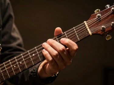 Close-up of hands gripping a guitar neck mid-chord under warm amber stage light, fretboard detail visible, motion slightly blurred at fingertips