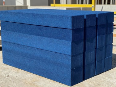 Extruded polystyrene blue foam insulation boards stacked neatly on an active Egyptian construction site, bright daylight, concrete textures, sharp focus
