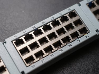 Overhead close-up of a 24-port Cat6A shielded patch panel on a neutral dark surface, numbered ports in sharp focus, consistent studio lighting, no text overlays