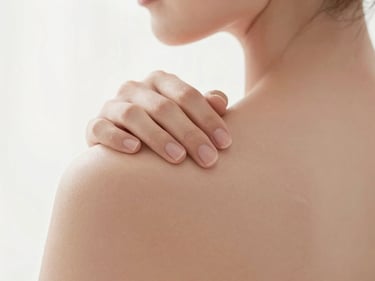 Soft-focus editorial shot of gentle touch on shoulders, warm lighting, clean white background