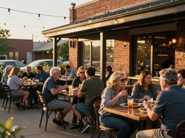 Outdoor patio of a casual Edwardsville restaurant at golden hour, string lights overhead, wooden tables with food and drinks, residents talking and eating in warm evening light