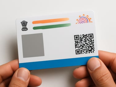 Close-up overhead shot of an Aadhaar card on a white surface under studio strobe light — crisp document edges, the blue strip and QR code clearly visible, hands lightly holding the card from the bottom, neutral background