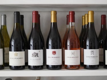 Straight-on studio shot of several wine and spirits bottles lined up on a clean white shelf, labels clearly visible, bright even lighting, no shadows